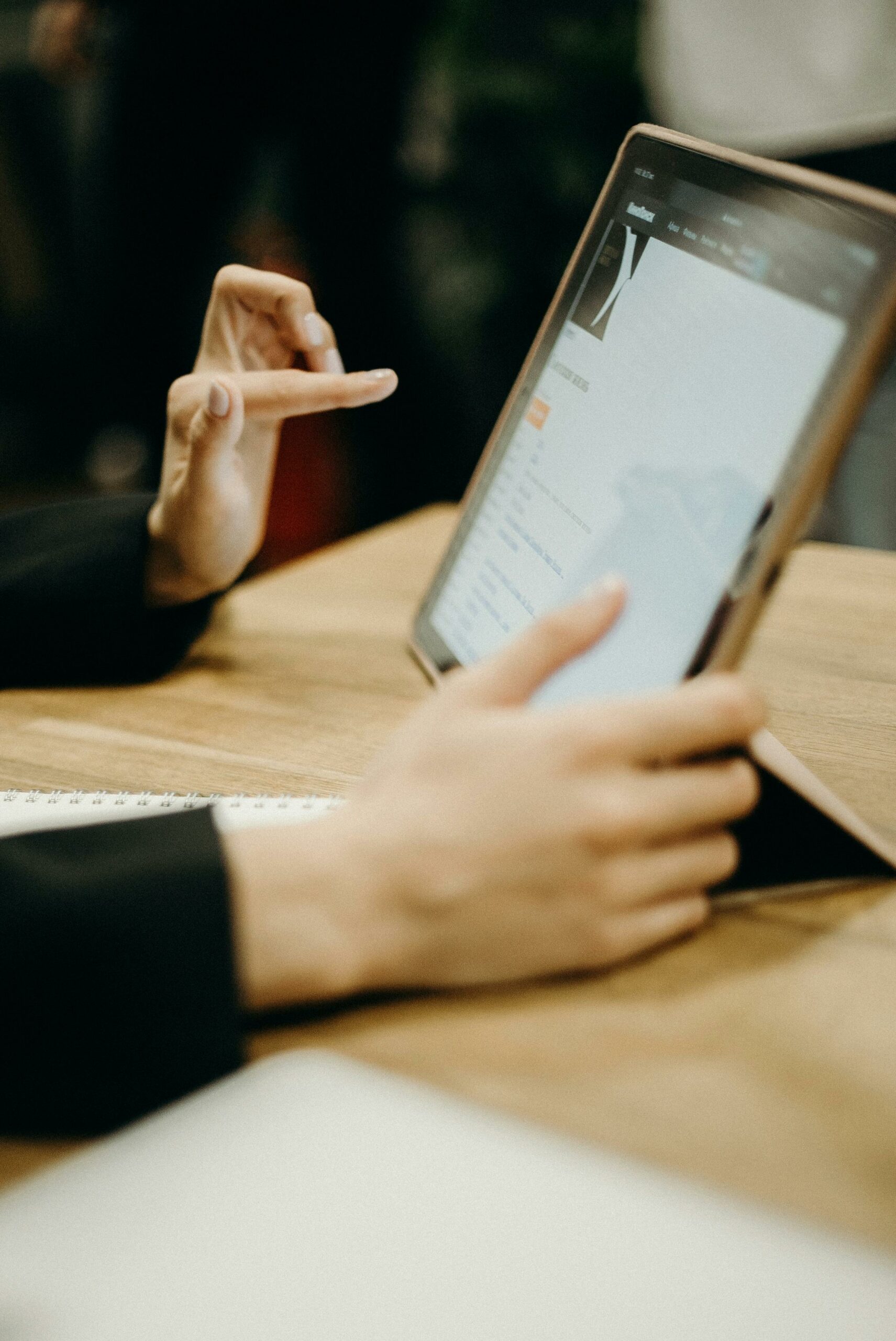 Close-up of hands working on a tablet in a sleek, modern office environment.